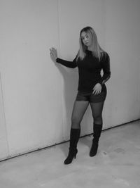 Portrait of a young woman standing against wall