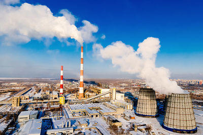 Smoke emitting from factory against blue sky