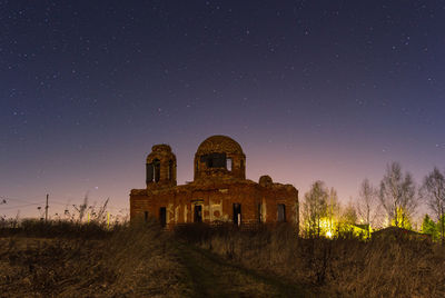 Old building on field against sky at night