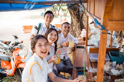 Portrait of smiling friends sitting on street