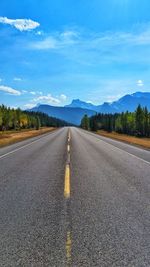 Road by mountains against sky