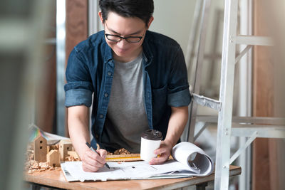 Mid adult man working in coffee cup on table