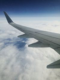 View of airplane wing against cloudy sky