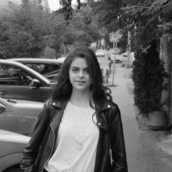 Portrait of young woman standing by trees