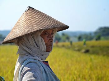 Close-up of senior female farmer wearing asian style conical hat at farm
