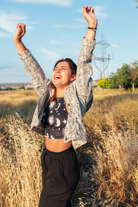 Teenage girl raising her arms laughing and feeling free