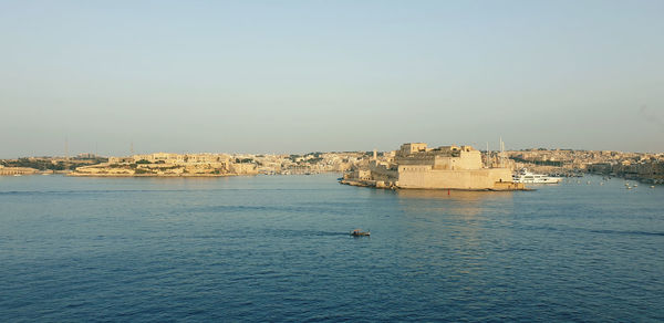 Buildings by sea against clear sky