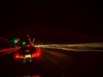 Cars on illuminated road against sky at night