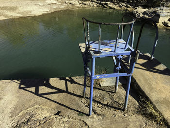 High angle view of empty chair at lakeshore