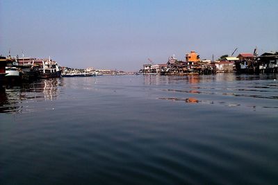 Reflection of buildings in sea against clear sky