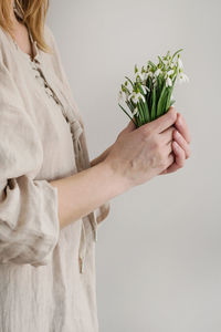 Midsection of woman holding plant against white background