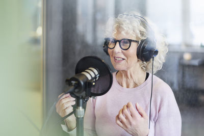 Mature woman sitting and hosting podcast or radio show or podcast