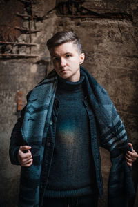 Portrait of young man standing against wall