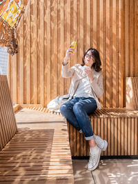 Full length of woman sitting on wooden floor