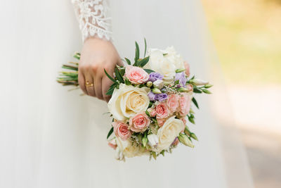 The hands of a young bride are holding a beautiful delicate wedding bouquet