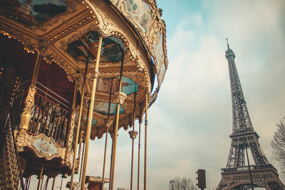 Low angle view of carousel and eiffel tower against sky