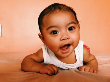 Close-up portrait of cute baby girl lying on bed at home
