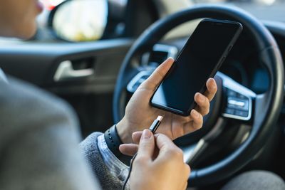 Midsection of woman plugging cable in smart phone