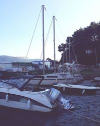 Boats moored at harbor against clear sky