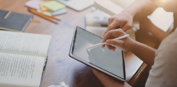 Midsection of businesswoman discussing over digital tablet with businessman in office