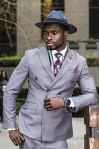 Young man looking away while standing outdoors