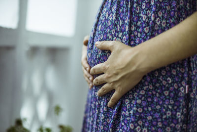 Close-up of woman hand against purple wall