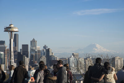 People by space needle in city against sky