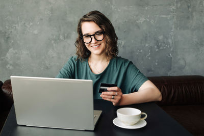 Effortless online shopping young woman holding credit card, making secure purchases on laptop