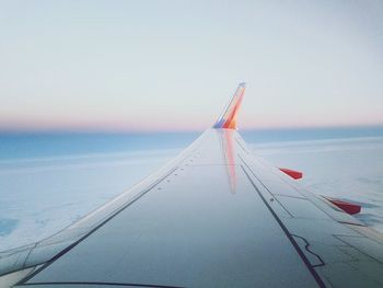 Close-up of airplane flying over sea against sky