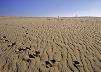 Scenic view of sand dunes against clear sky