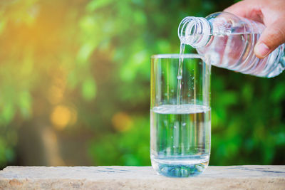 Cropped hand pouring water in glass at table