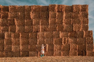 Mid adult woman standing against hay bales