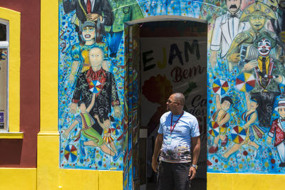 Full length of man standing against graffiti wall