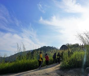 Rear view of people standing on road against sky