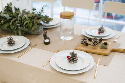 Christmas festive table setting of a festive dinner. pine cone on a white plate