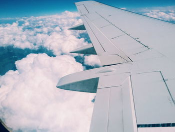 Cropped image of airplane flying over cloudscape against sky