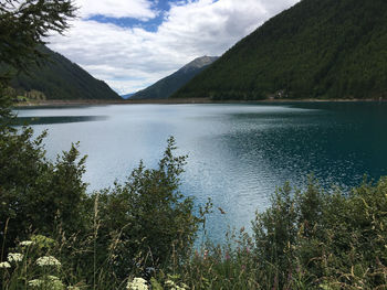 Scenic view of lake by mountains against sky