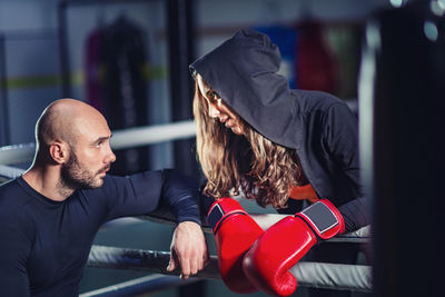Female boxer talking with male coach in gym
