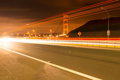 Light trails on road against sky at night