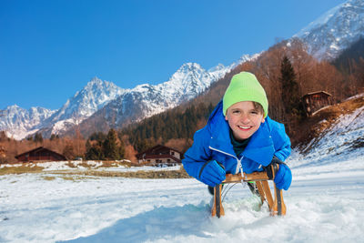 Portrait of smiling woman standing on snowcapped mountains against sky