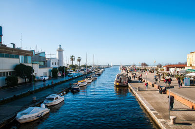 Boats in canal amidst buildings in city against clear sky