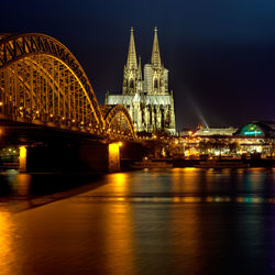 Illuminated hohenzollern bridge against cologne cathedral and buildings at night