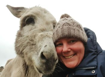 Portrait of smiling woman with donkey against sky