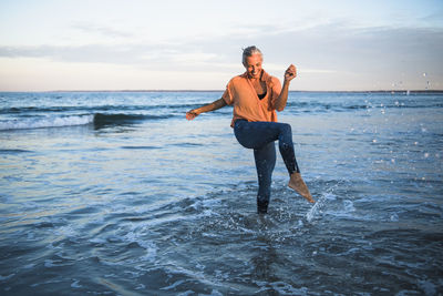 Gray haired woman playing at the beach for sunset