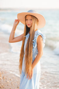 Beautiful smiling blonde teenager girl 12-14 year old with long hair wear straw hat dress over sea