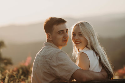 Side view of couple sitting on field