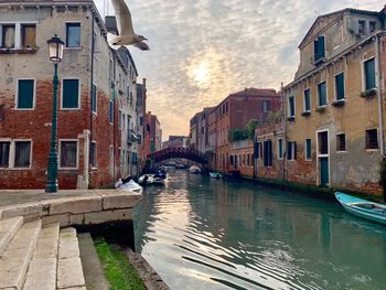 Canal amidst buildings in city against sky