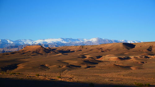 Scenic view of desert against clear blue sky