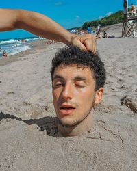 Portrait of young man on sand at beach