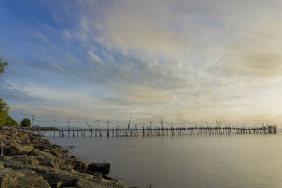 Bridge over sea against sky during sunset